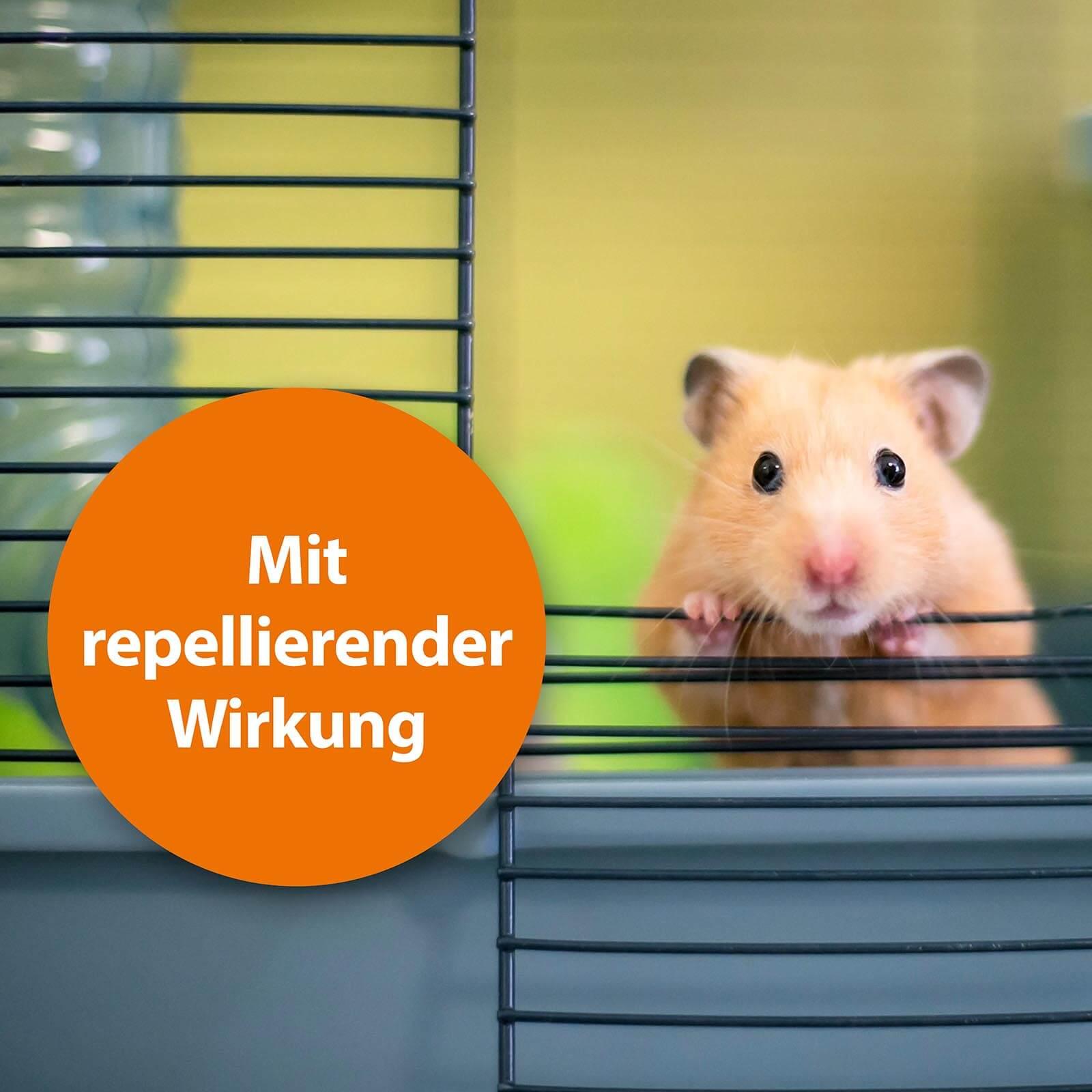 Goldhamster schaut aus Käfig mit der Schrift "Mit repellierender Wirkung"